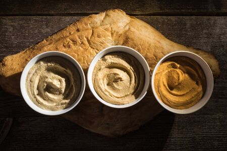 top view of delicious assorted hummus on fresh baked pita on wooden rustic table
