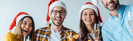 panoramic shot of happy businessmen and multicultural businesswomen holding sparklers and champagne glasses in officeの写真素材