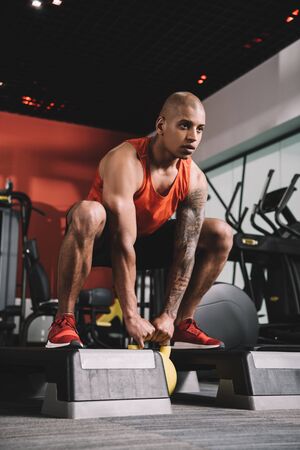 young african american sportsman lifting weight in gymの写真素材