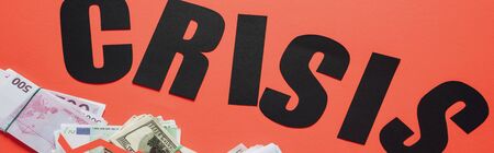panoramic shot of black word crisis near dollar, euro and ruble banknotes on red background