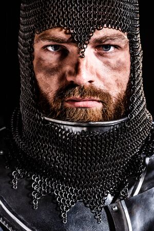 handsome knight in armor looking at camera isolated on blackの写真素材