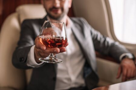 selective focus of glass with cognac in hand on businessman