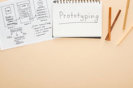 top view of website design template, felt-tip pens and notebook with prototyping lettering on beige...