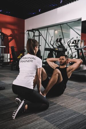 young trainer supervising handsome sportsman doing push upsの写真素材