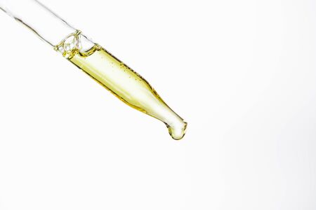dropper and drop of natural serum isolated on whiteの写真素材