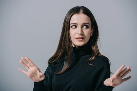 stylish shocked woman gesturing and posing in black sweater, isolated on grey