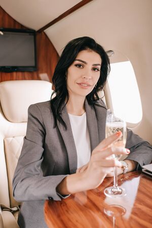 attractive businesswoman holding champagne glass in private jet