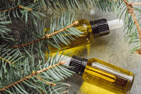 top view of bottles with natural oil near fir branches on grey stone surfaceの写真素材