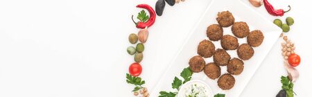 top view of vegetables arranged in round frame around falafel on plate with sauce on white background, panoramic shotの写真素材