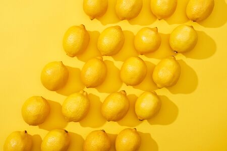 top view of ripe lemons on yellow background