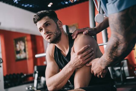 cropped view of african american doctor examining injured shoulder of young sportsmanの写真素材