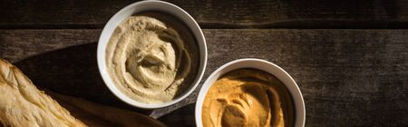 top view of delicious assorted hummus near fresh baked pita on wooden rustic table, panoramic shotの写真素材