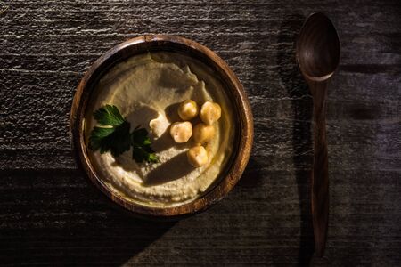 top view of delicious hummus with chickpeas in bowl on wooden rustic tableの写真素材
