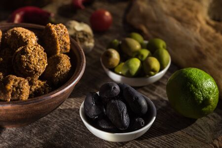 selective focus of delicious falafel balls near lime, black and green olives on wooden rustic tableの写真素材