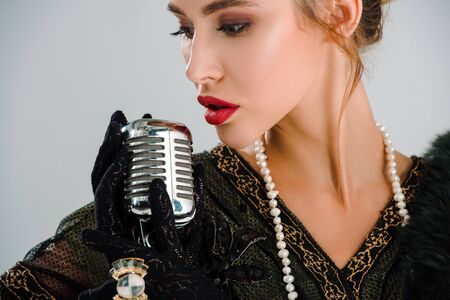 beautiful woman touching vintage microphone isolated on greyの写真素材