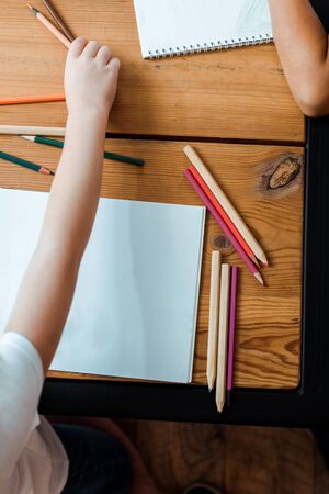 top view of kid taking color pencil near child