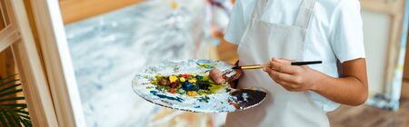 panoramic shot of kid holding colorful palette with gouache paintの写真素材