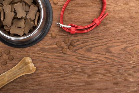 top view of dry pet food in silver bowl near bone, collar on wooden tableの写真素材