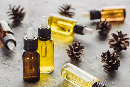selective focus of bottles with natural oil near dry cones on grey stone surfaceの写真素材