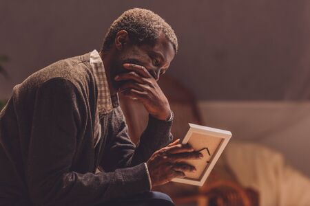 senior, depressed african american man looking at photo frameの写真素材