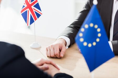 cropped view of ambassadors sitting near european union and united kingdom flags