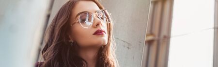 elegant girl posing in trendy burgundy suit and sunglasses on urban roof