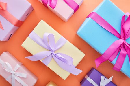 flat lay with multicolored gift boxes with ribbons and bows on orange backgroundの写真素材
