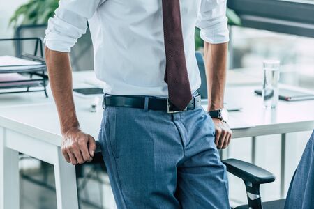 cropped view of businessman standing near workplace in officeの写真素材