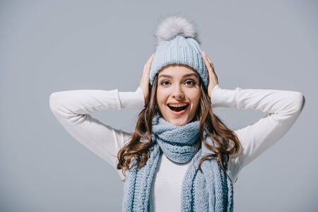 excited girl posing in blue knitted hat and scarf, isolated on greyの写真素材