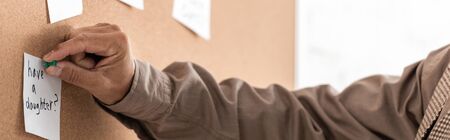 panoramic shot of retired man with alzheimer holding pin near papers on boardの写真素材