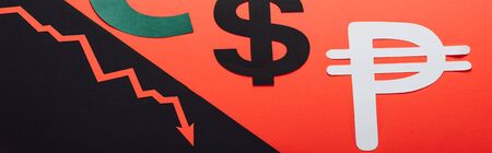 panoramic shot of dollar and peso symbols, and recession arrow on red and black background divided by sloping lineの写真素材