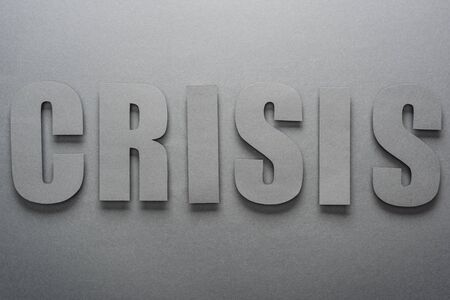 top view of paper cut word crisis on grey background with shadowsの写真素材