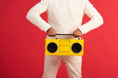 cropped view of man holding retro boombox isolated on redの写真素材
