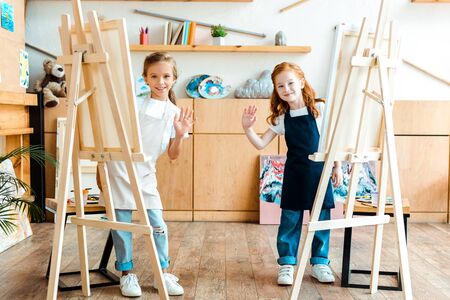 happy kids smiling and waving hands in art schoolの写真素材