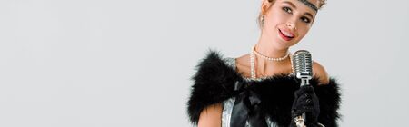 panoramic shot of happy woman near retro microphone isolated on whiteの写真素材