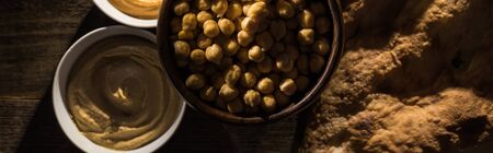 top view of delicious assorted hummus, chickpeas and fresh baked pita on wooden rustic table,...