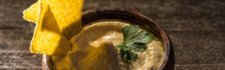 delicious hummus in bowl with nachos on wooden rustic table, panoramic shotの写真素材
