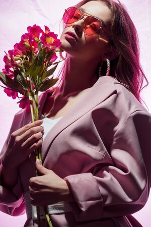 pretty woman in sunglasses holding flowers on whiteの写真素材