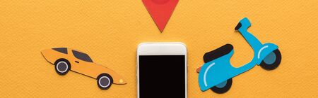 top view of paper cut vehicles near location mark and smartphone with blank screen on orange...
