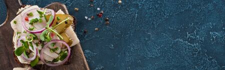 panoramic shot of rye bread with smorrebrod sandwich near peppercorns on blue surface