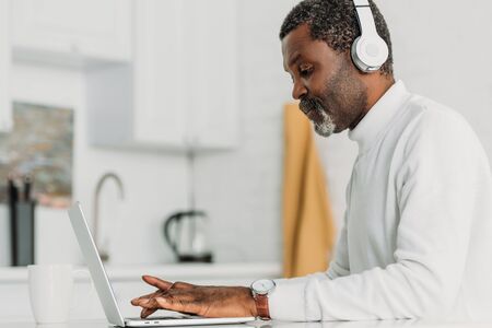 concentrated african american man in headphones typing on laptopの写真素材