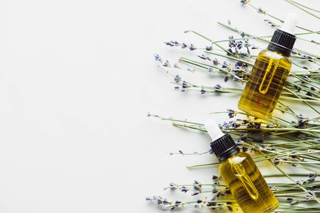 top view of dry lavender twigs with flowers and bottles with natural oil on white backgroundの写真素材