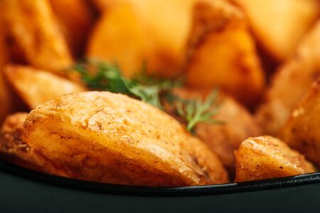 close up view of delicious golden potato wedges with dill in bowlの写真素材