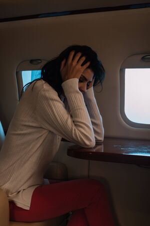 scared woman with airsickness touching hair in private jetの写真素材