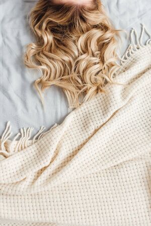 cropped view of blonde woman lying on bedの写真素材