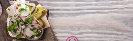 panoramic shot of rye bread with fresh smorrebrod sandwich on wooden surfaceの写真素材