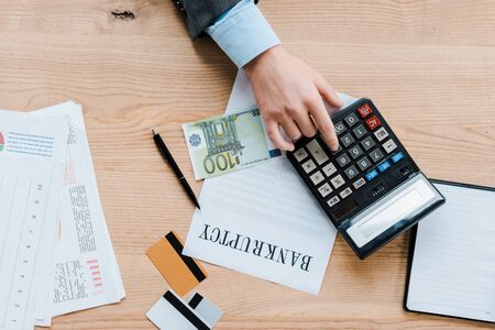 top view of businessman using calculator near euro banknote and credit cards