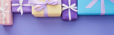 flat lay with colorful gifts with bows on purple background with copy space, panoramic shot
