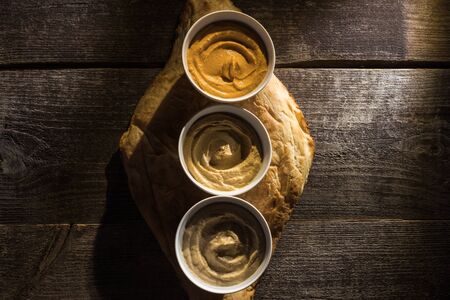 top view of delicious assorted hummus on fresh baked pita on wooden rustic table