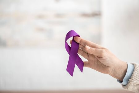 cropped view of woman holding purple ribbon at homeの写真素材